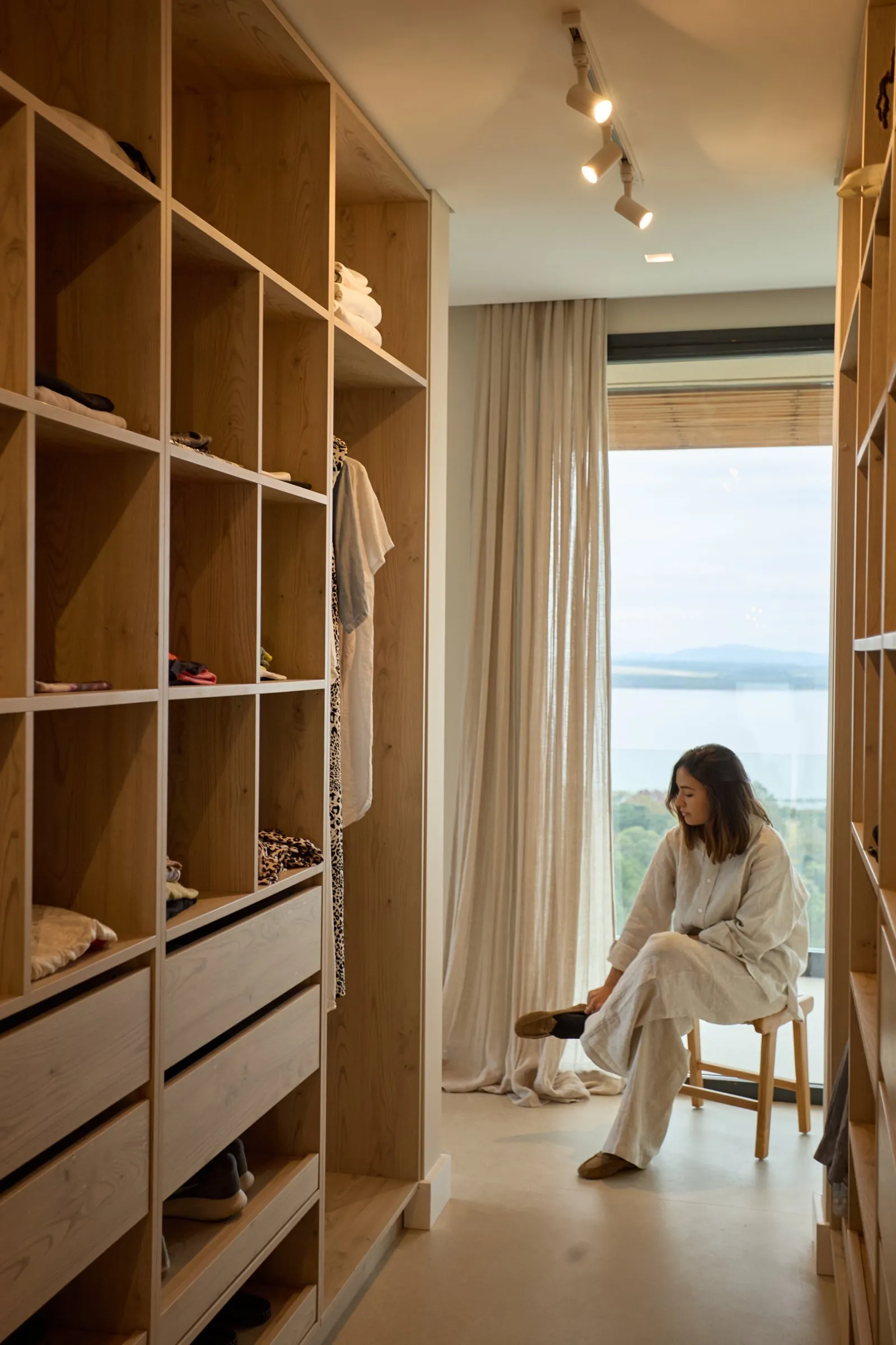 Comedor con mesa larga de madera, sillas negras y vista a los árboles