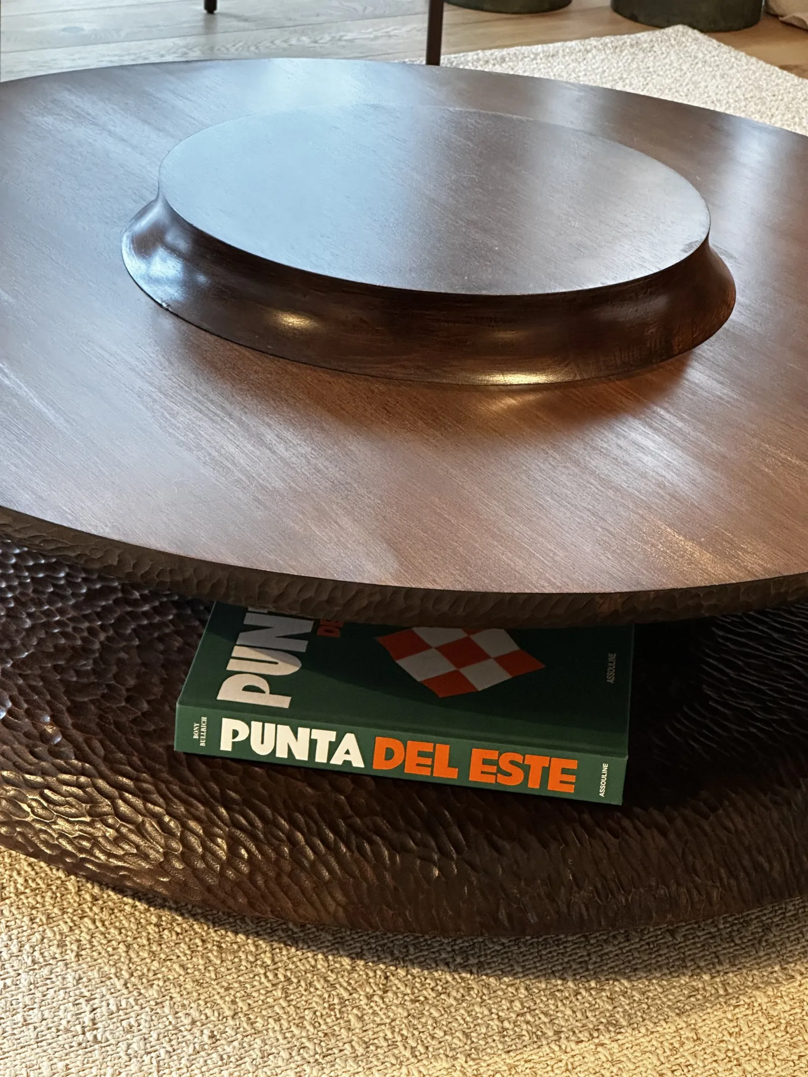 Mesa de centro redonda de madera, con libros y un cuenco de cerámica