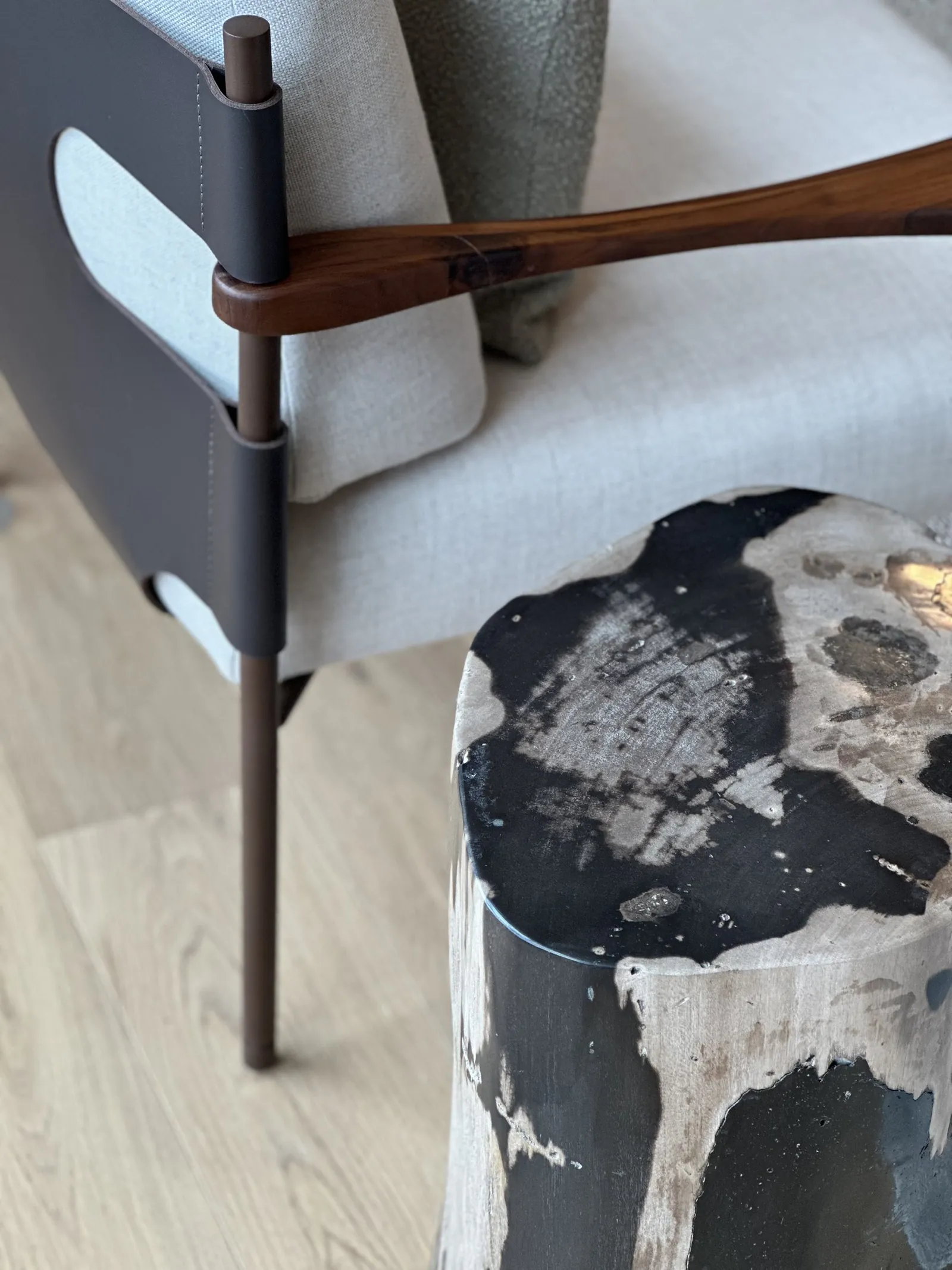 Apoyabrazos de madera de un sillón, junto a una mesa auxiliar redonda