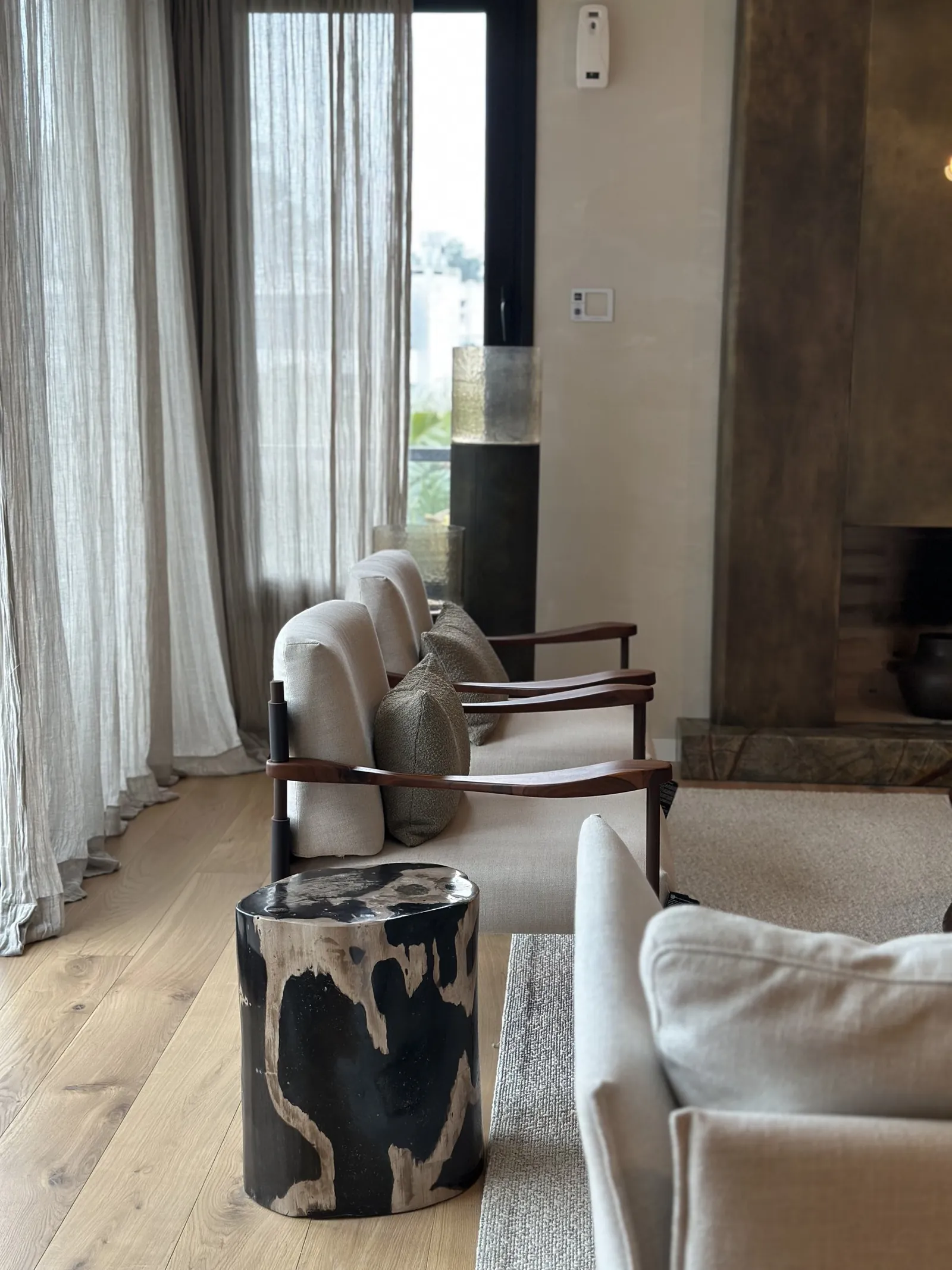 Estar con sillones de brazos de madera, una mesa redonda y una chimenea metálica