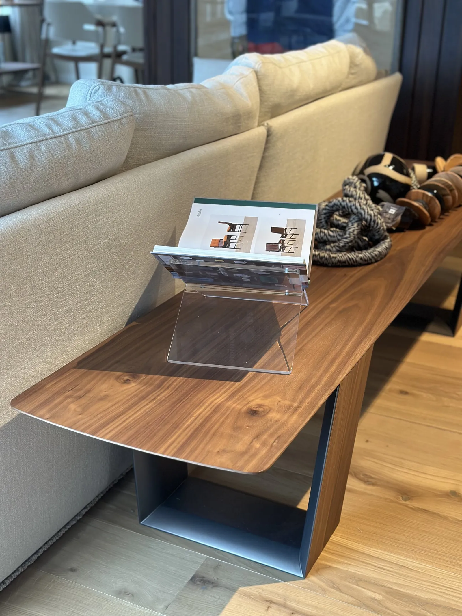 Consola de madera junto a un sofá, con un revistero y una cuerda anudada