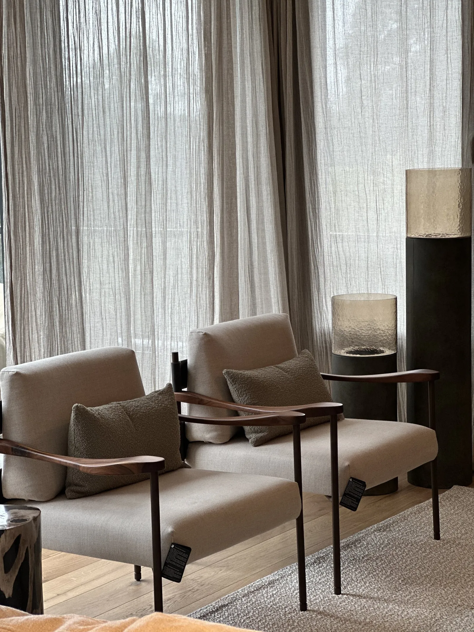 Estar con dos sillones de brazos de madera, almohadones verdes y lámparas de pie