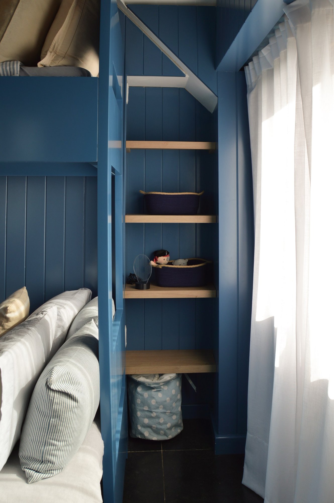 Dormitorio infantil con muros azules y nichos de roble